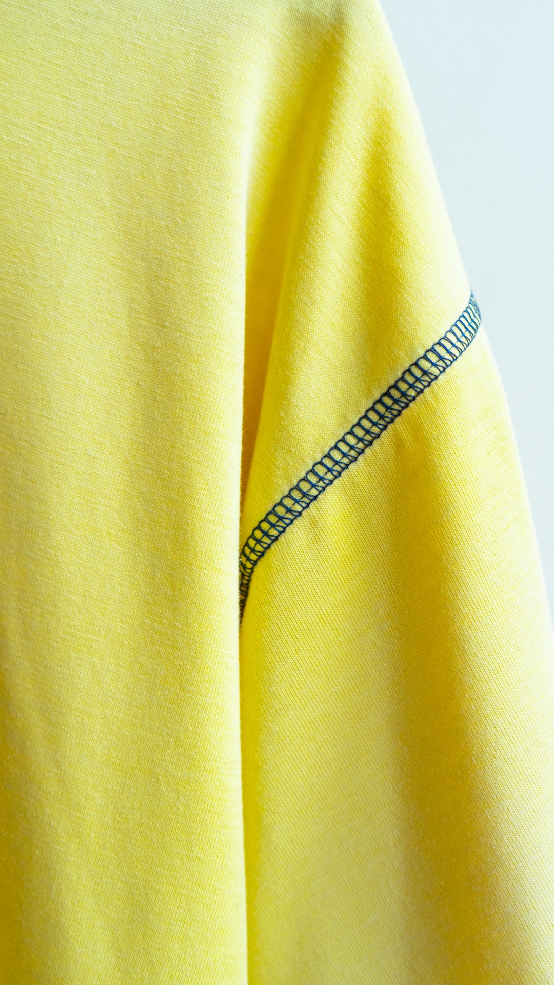 detail of sleeve of secondhand blue and yellow sportswear T-shirt fresh vintage