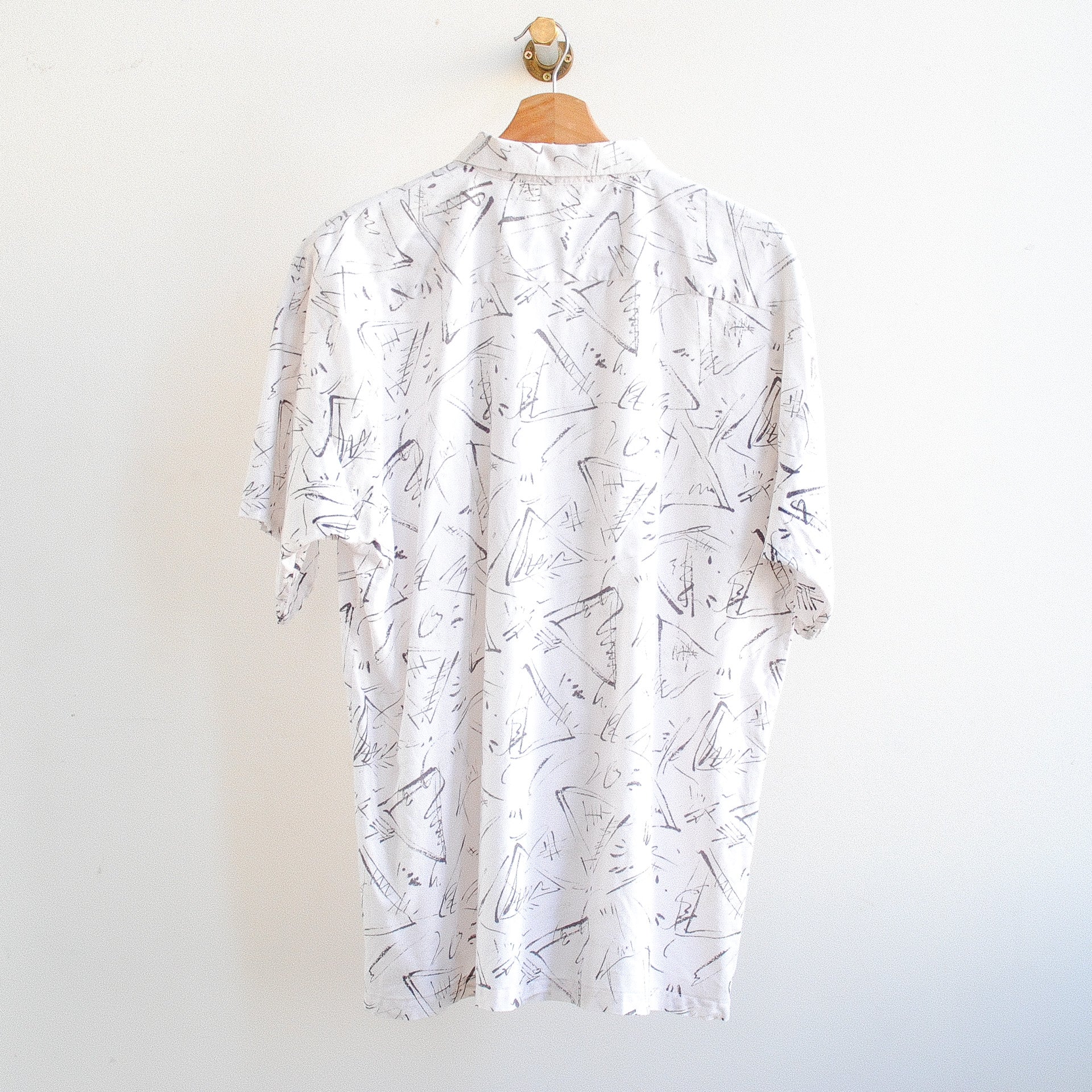 back of white vintage shirt with black pattern on a hanger in 80s or 90s style