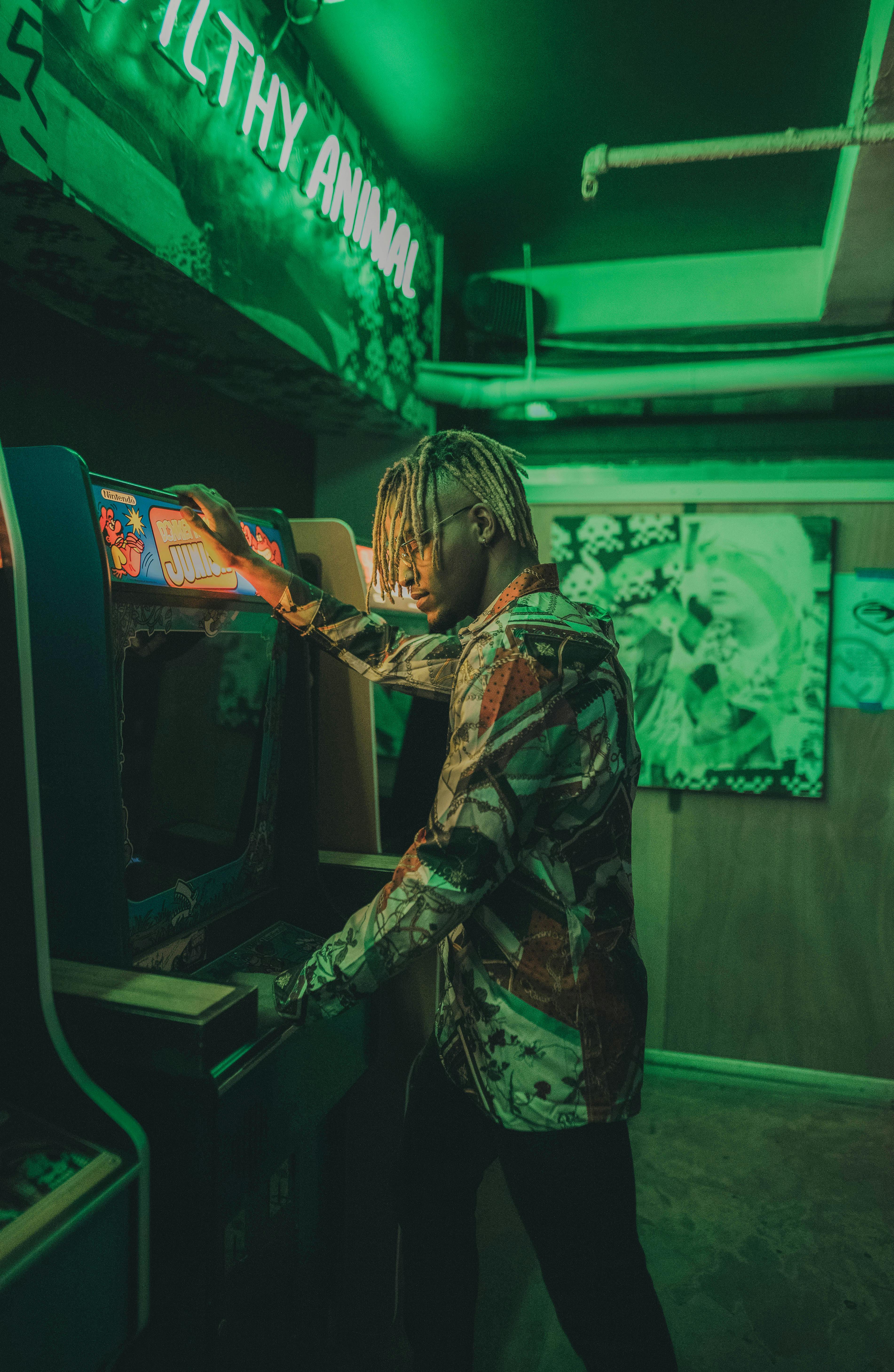 black young man wearing a vintage shirt playing an arcade video game