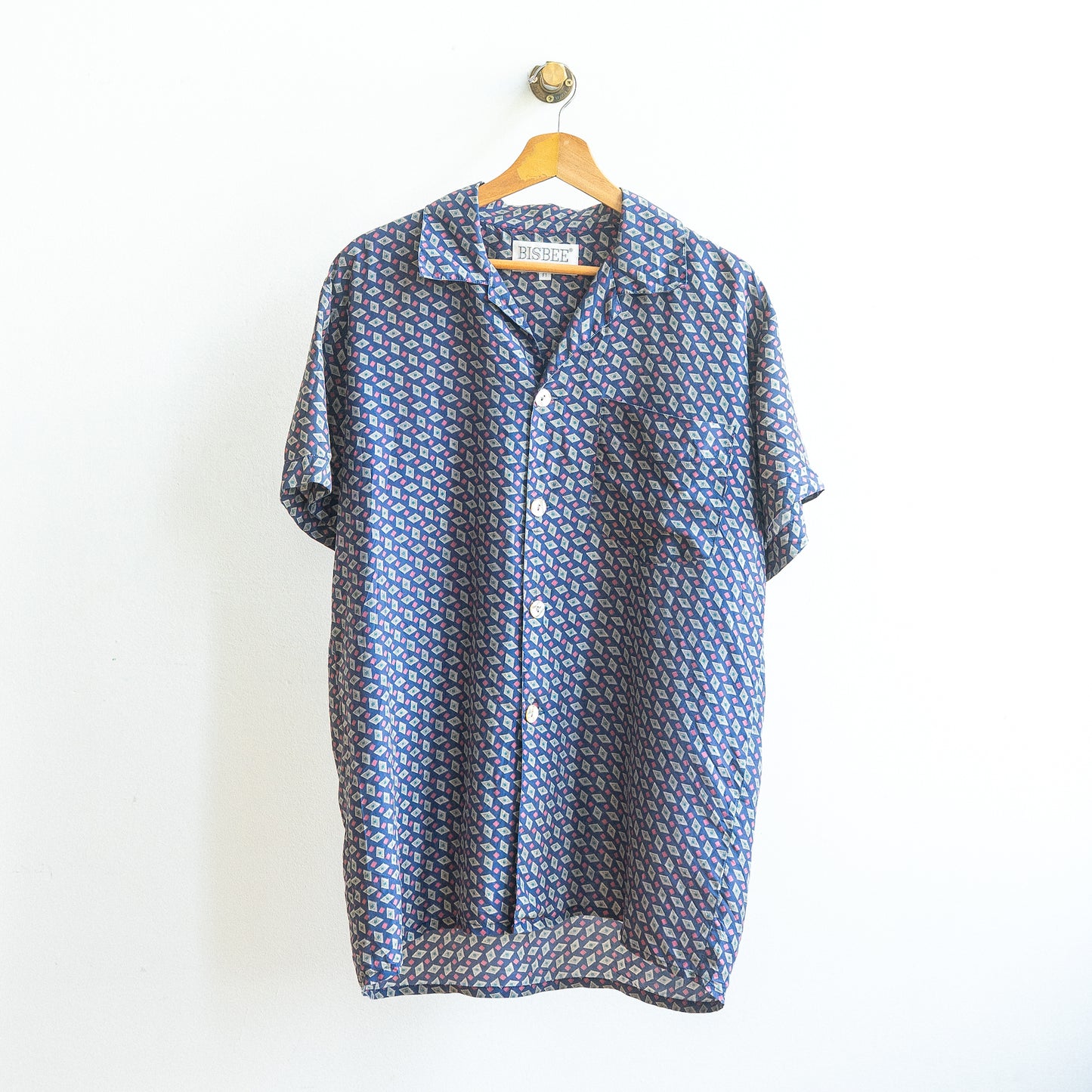 blue vintage shirt with pink and white in detailed pattern and buttons on a hanger