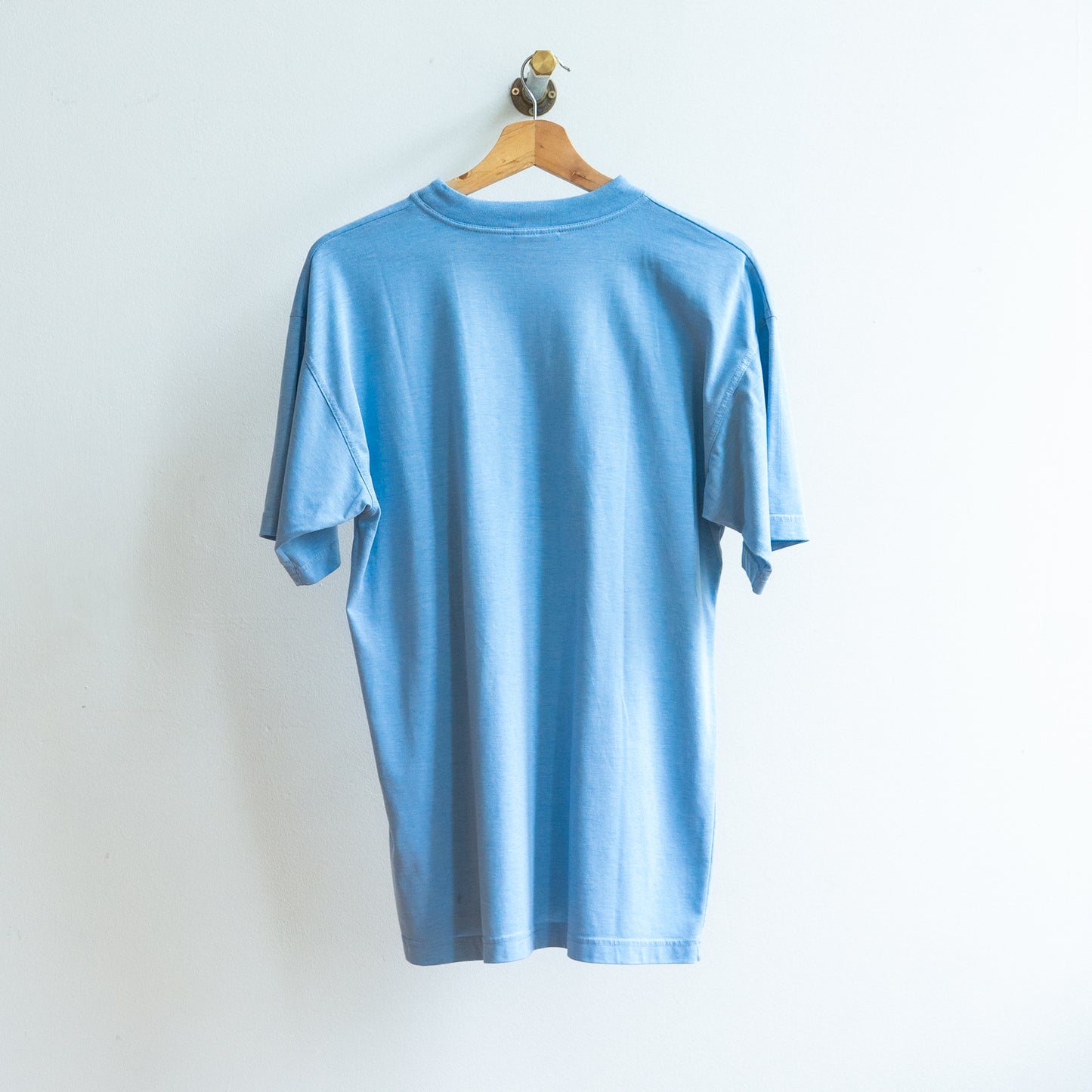 achterkant van lichtblauwe tweedehands tshirt op kapstok 
