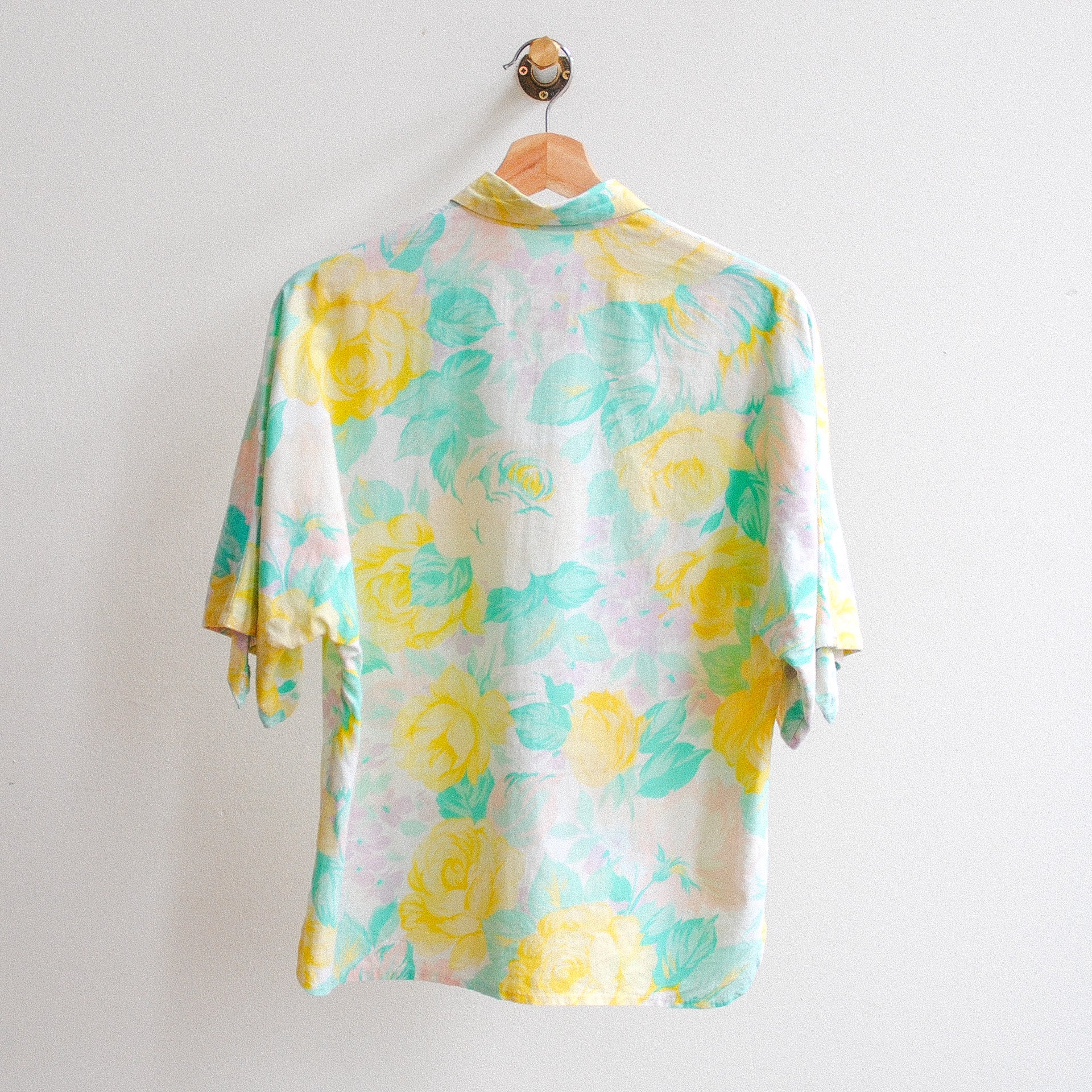 afbeelding-van-vintage-blouse-aan-kapstok-met-grote-gele-bloemen-in-combinatie-met-wit-en-groen