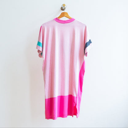 Back of a pink and white oversized t-shirt or dress from the 80s with short sleeves on which are asymmetrical color accents in teal and black