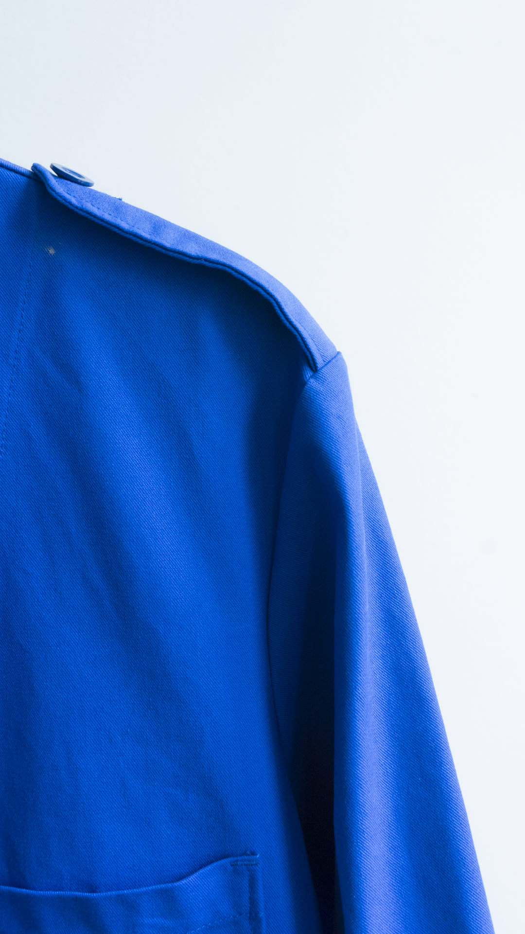detail of fabric and should of a long blue vintage worker coat in a french style