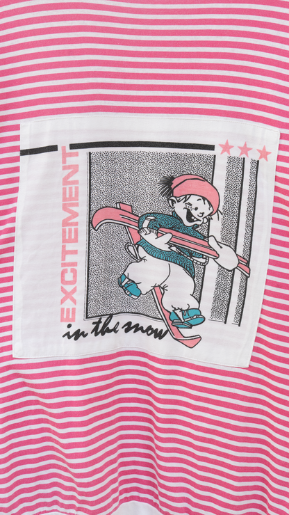 zoom-in print of a child with skis and the text 'excitement in the snow' of a pink white striped 80s oversized sleep t-shirt