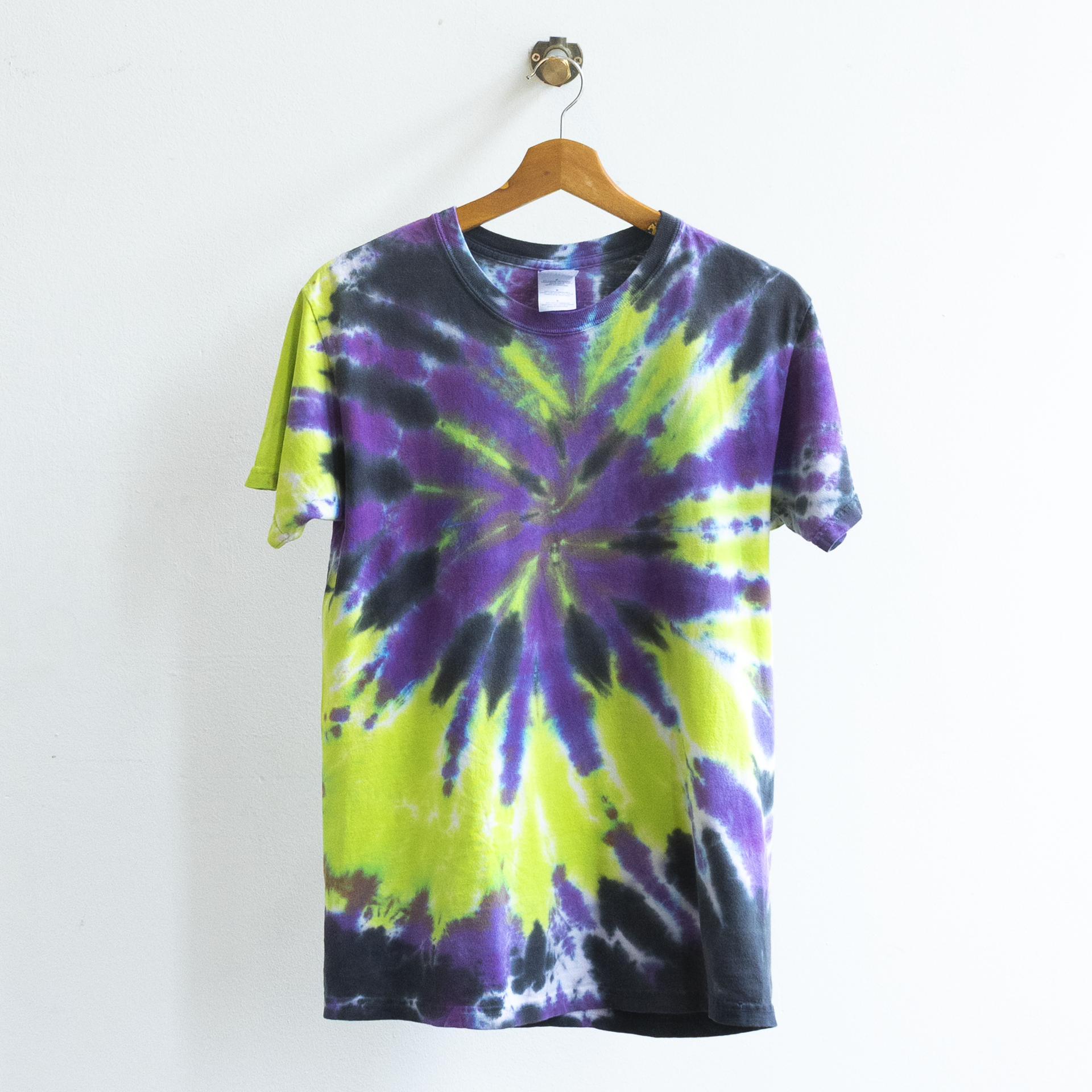 A short-sleeve vintage grunge tie-dye t-shirt with a spiral pattern in purple, lime green, and black