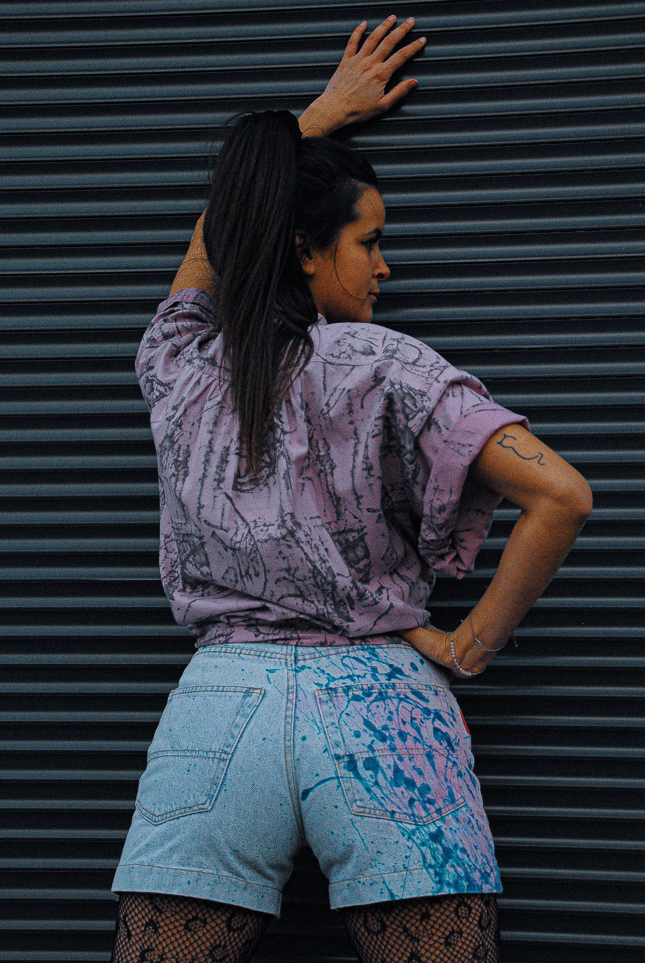 zoomed-picture-of-fresh-vintage-light-jeans-shorts-with-blue-and-pink-paint-splatters-on-the-back-assymetrically-leaning-towards-garage-door