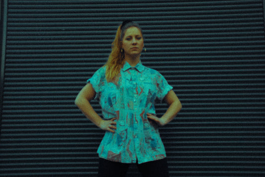 artsy picture of a young woman in front of a garage door wearing an abstract shirt and big round earrings 90s classy ghetto style 