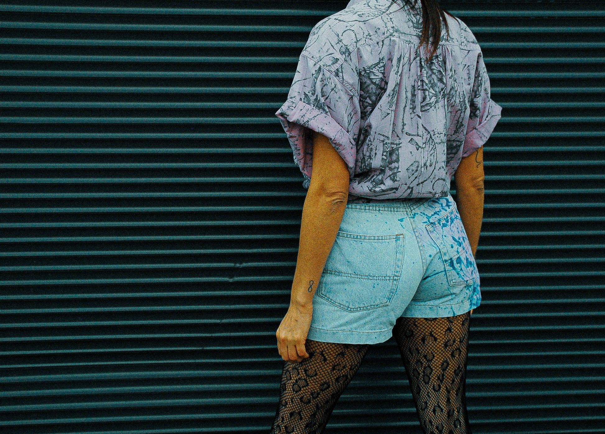 achterkant-paars-vintage-hemd-mouwen-opgerold-en-dichtgeknoopt-gedragen-op-lichte-jeans-short-met-verf-en-panter-broekkousen