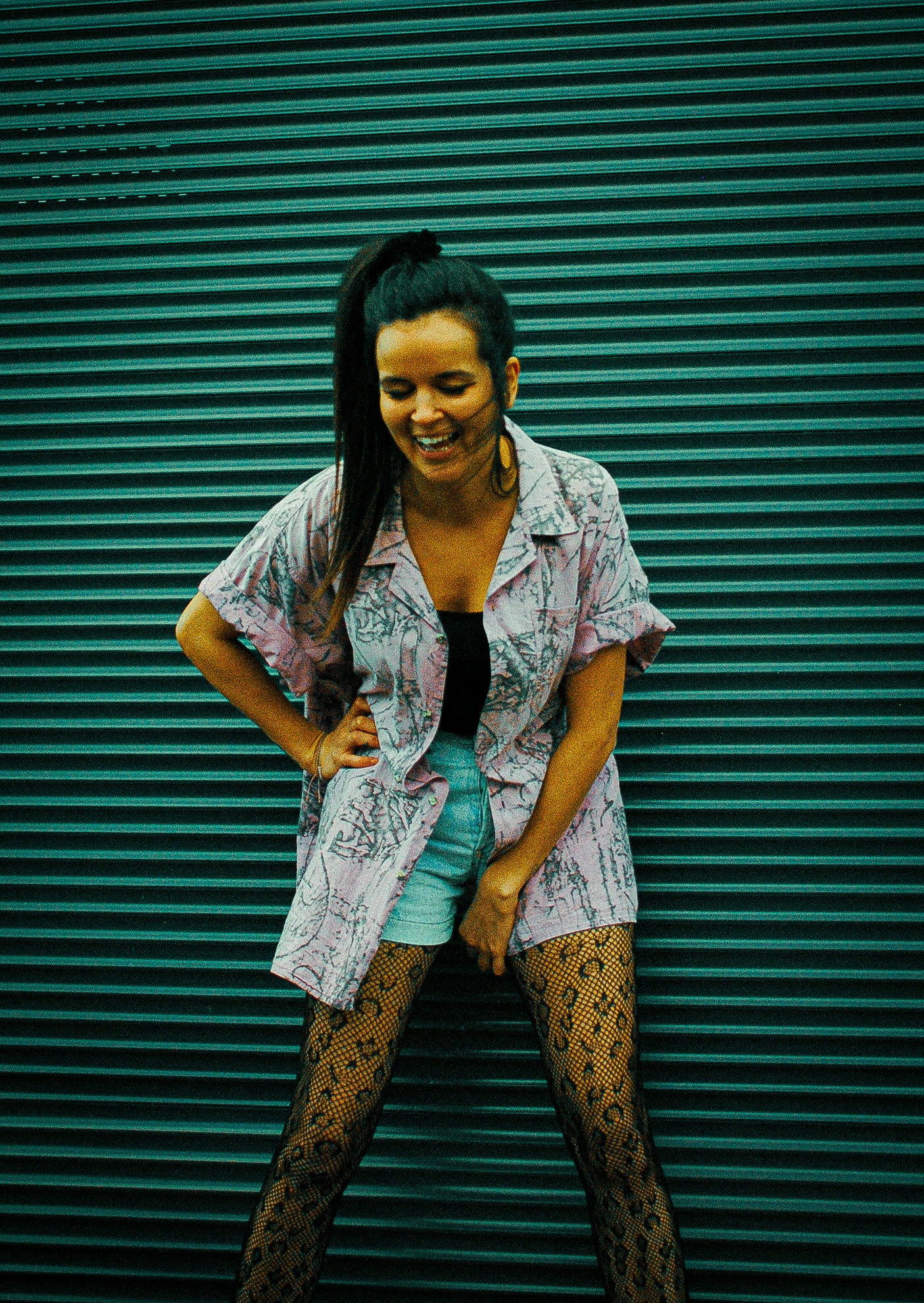 vrouw-voor-garagepoort-paars-vintage-hemd-hand-in-zij-lachend